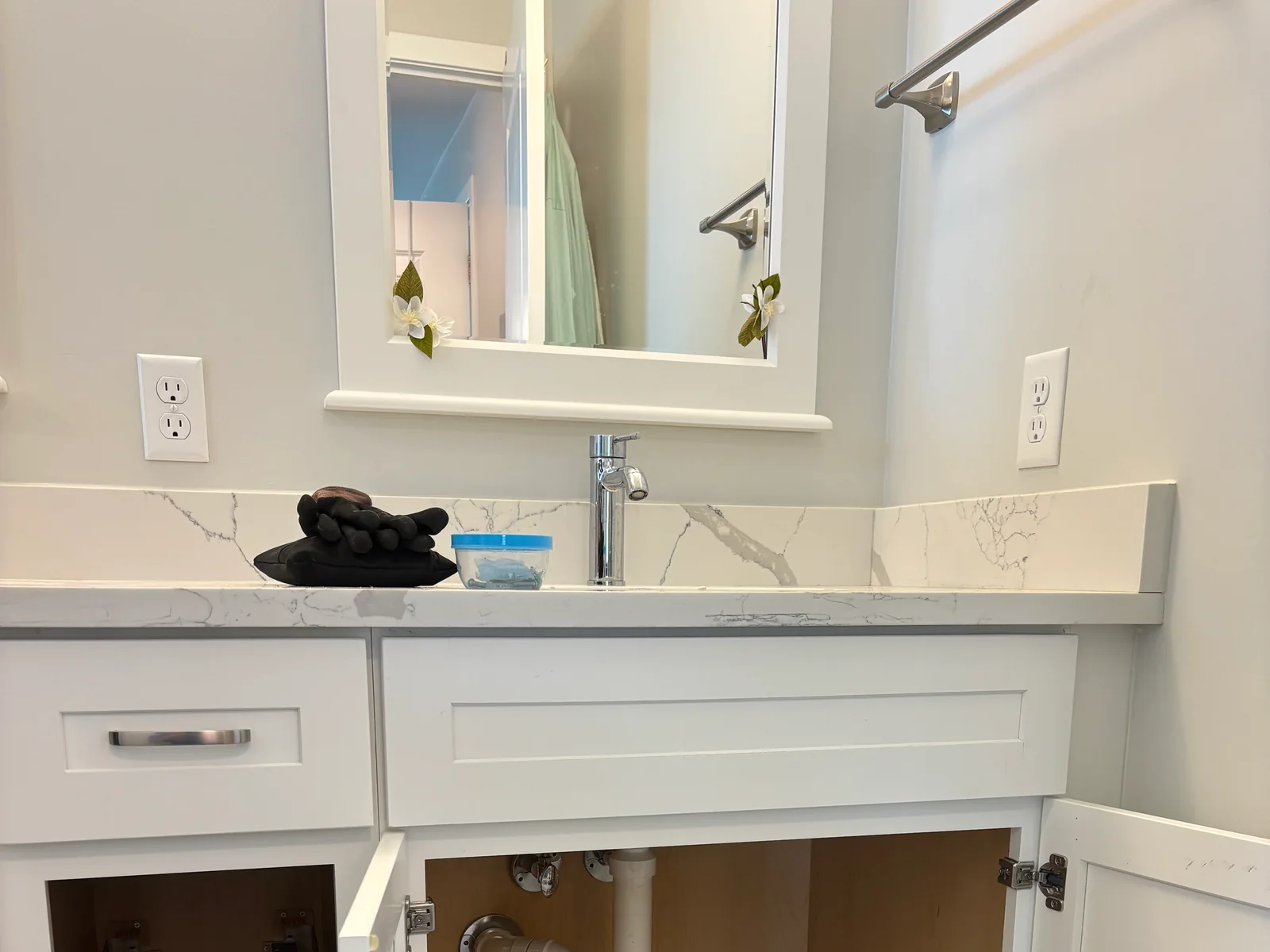 Finished bathroom vanity with wall receptacle and illuminated mirror area