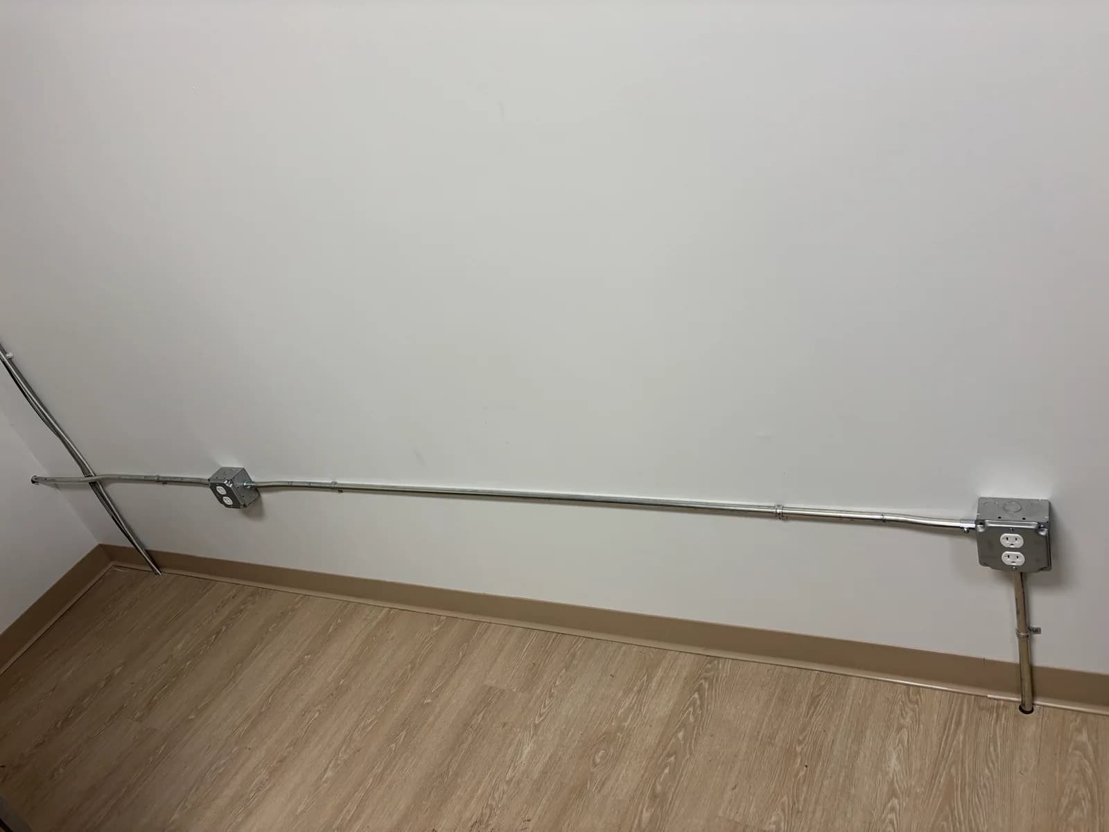 Surface-mounted conduit connecting receptacles along a finished commercial wall