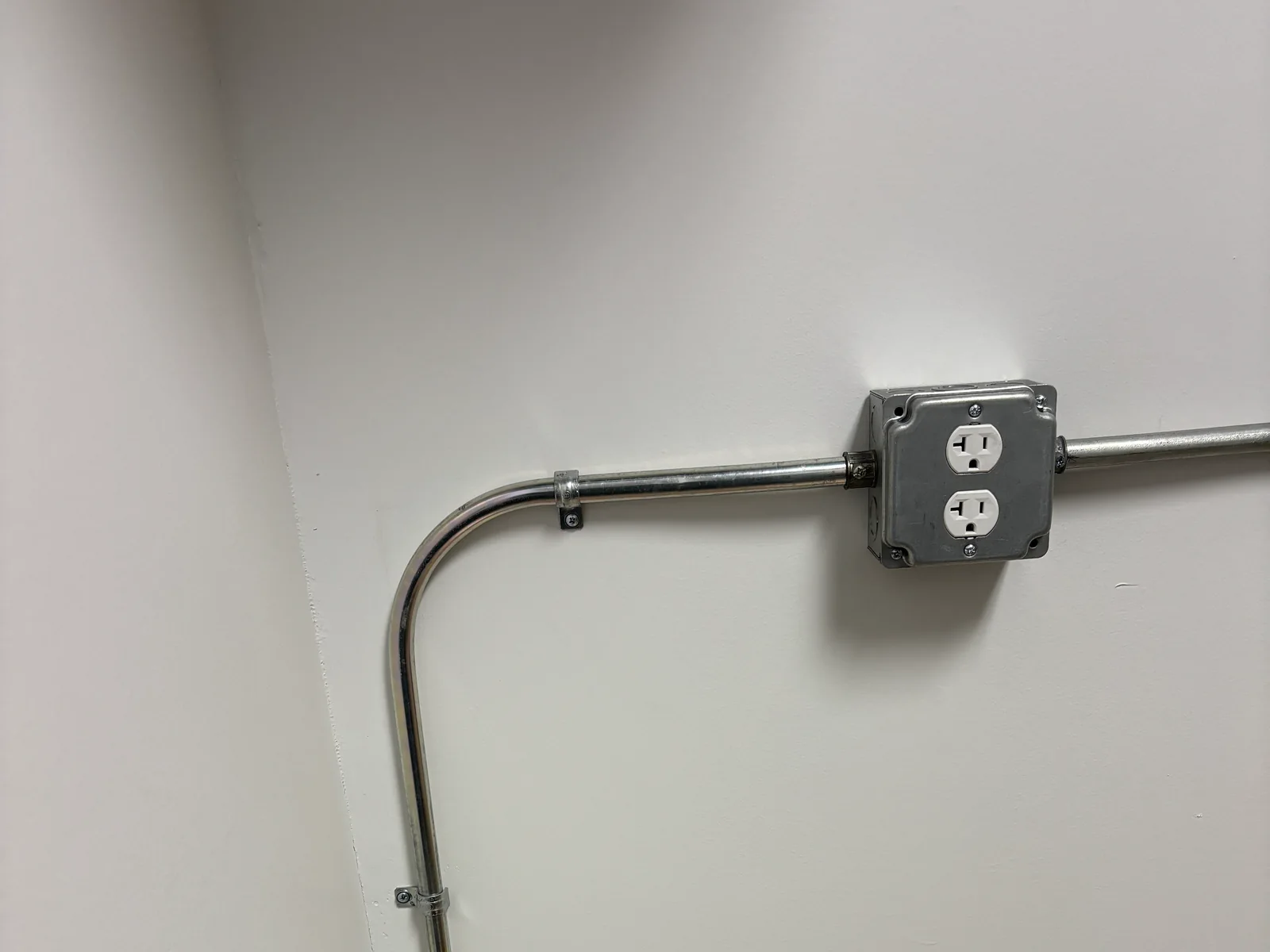 Metal conduit entering a surface-mounted commercial receptacle