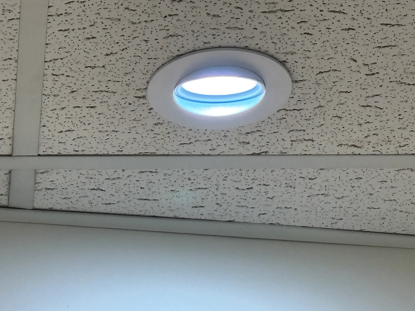 Illuminated round recessed light installed in an acoustic ceiling tile