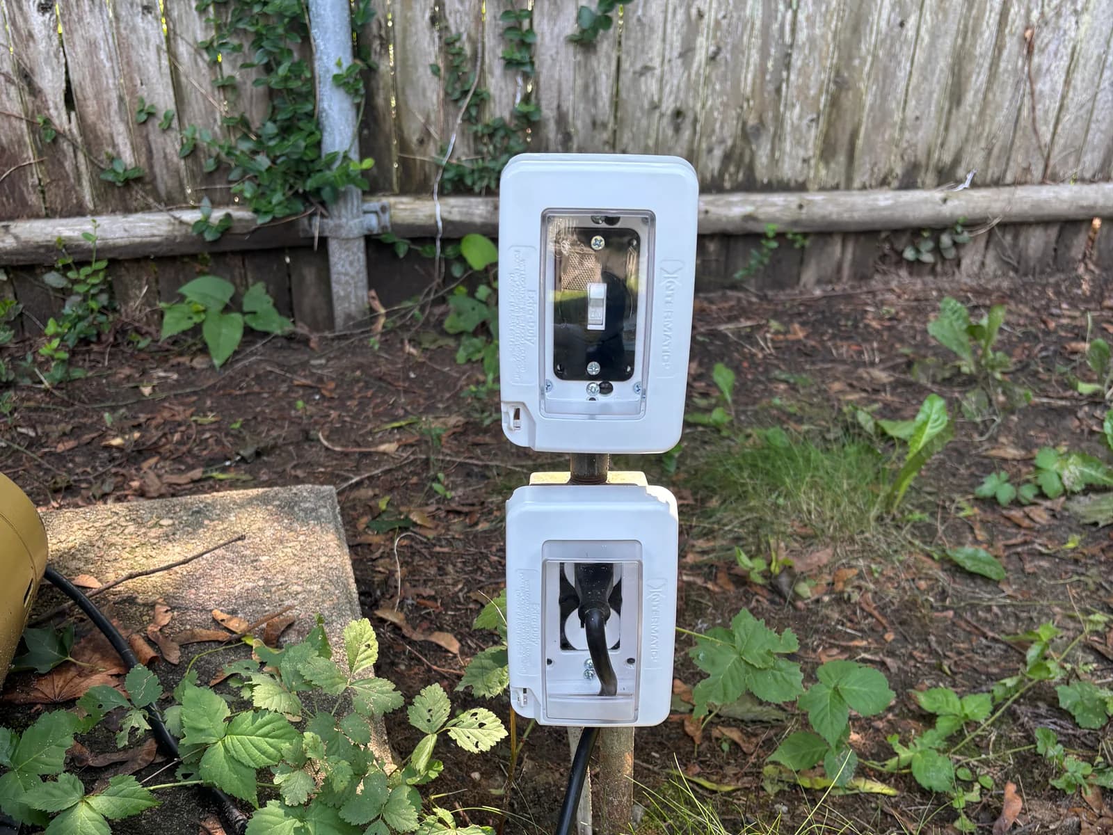 Two weather-resistant electrical enclosures installed beside landscaping