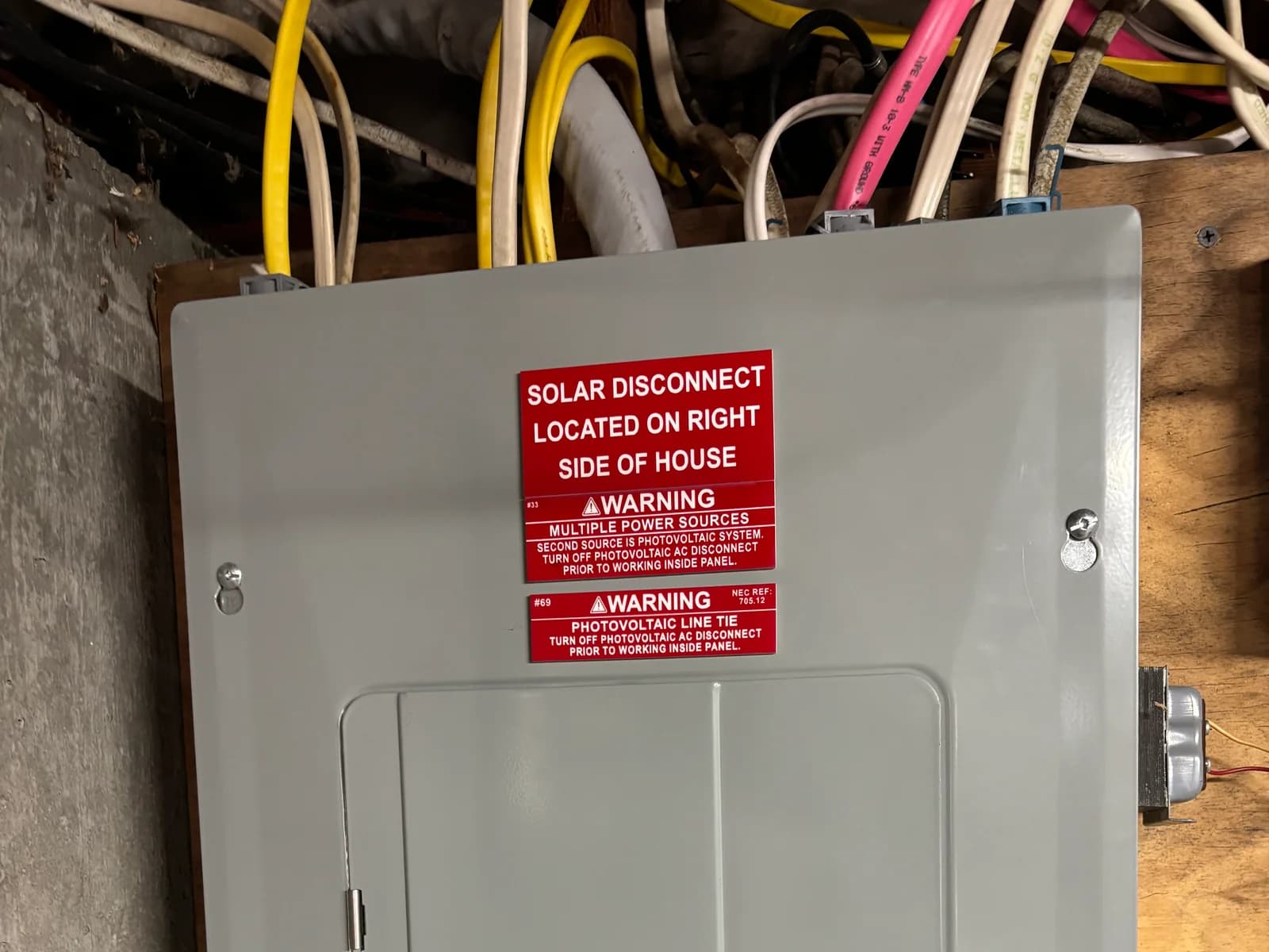 Labeled solar electrical disconnect mounted beside exterior siding